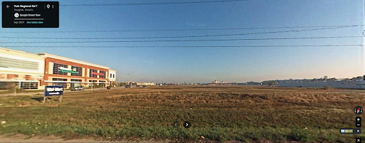 A 2007 Google Street View image captured looking north from Highway 7 in Vaughan, Ontario, showing an empty brown field and a sprawling low-rise commercial building under a clear sky.