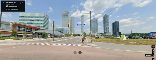 A 2025 Google Street View image from the exact same vantage point looking north on Highway 7, now transformed into a high-density urban core featuring modern high-rise glass towers, a subway station, widened roads, and crosswalks.